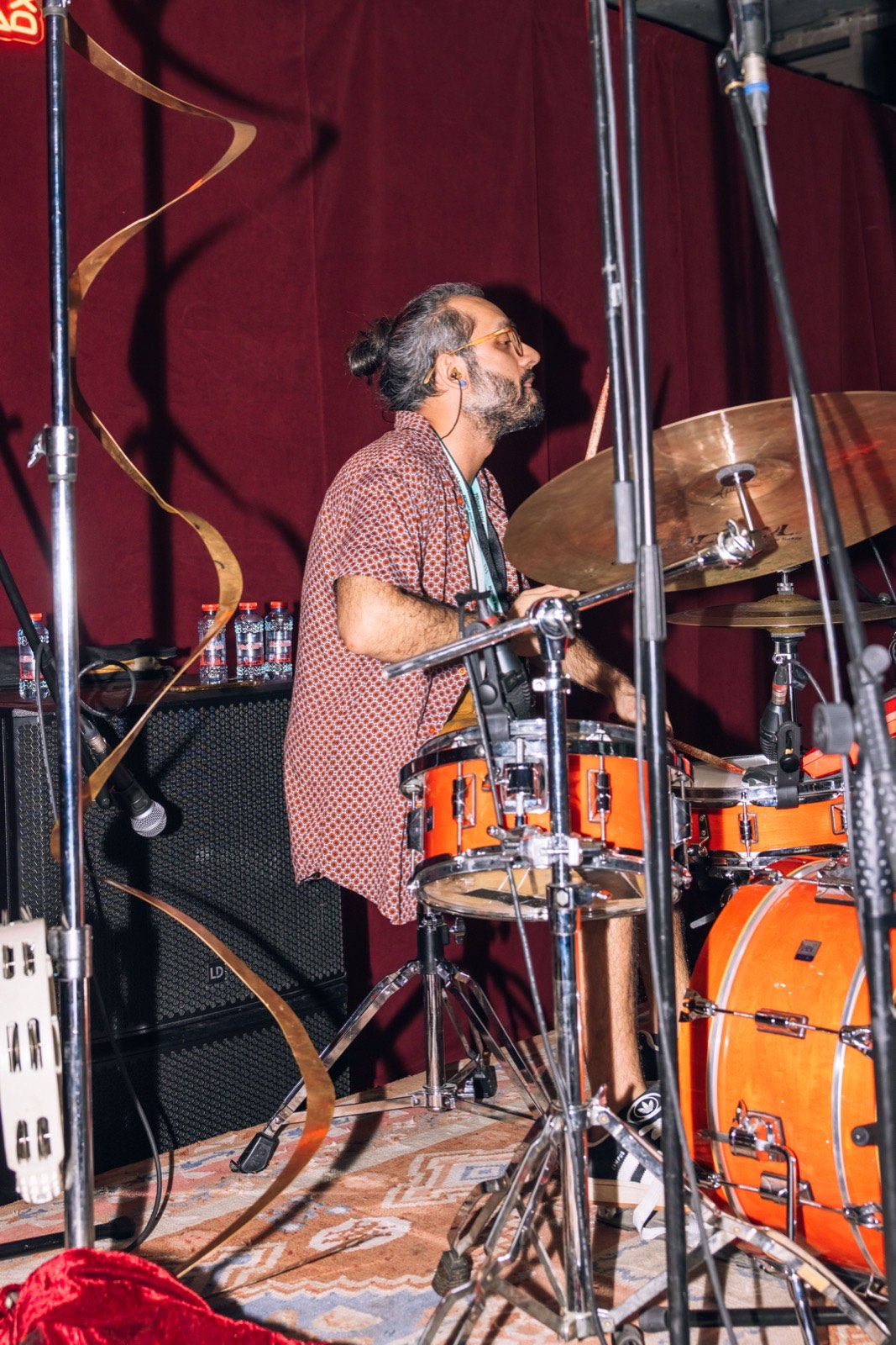 A drummer playing an orange drum kit on stage.