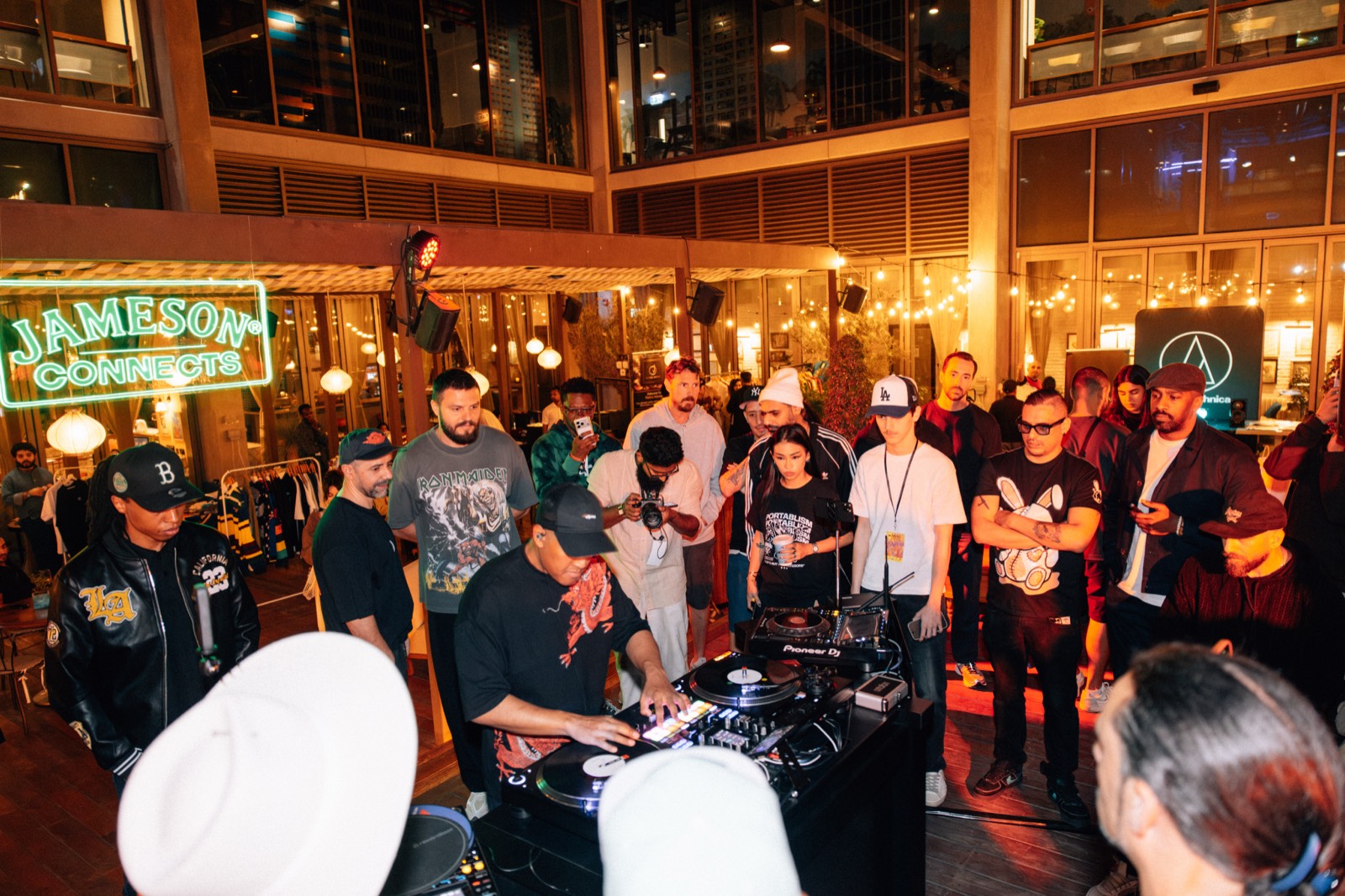 A crowd gathered around the decks under a Jameson Connects neon sign in the courtyard.