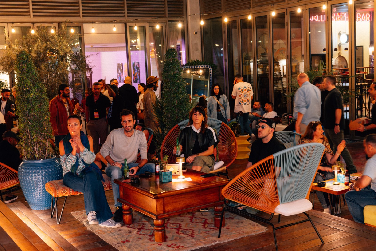 People sitting on rattan chairs in the courtyard under strings of lights.