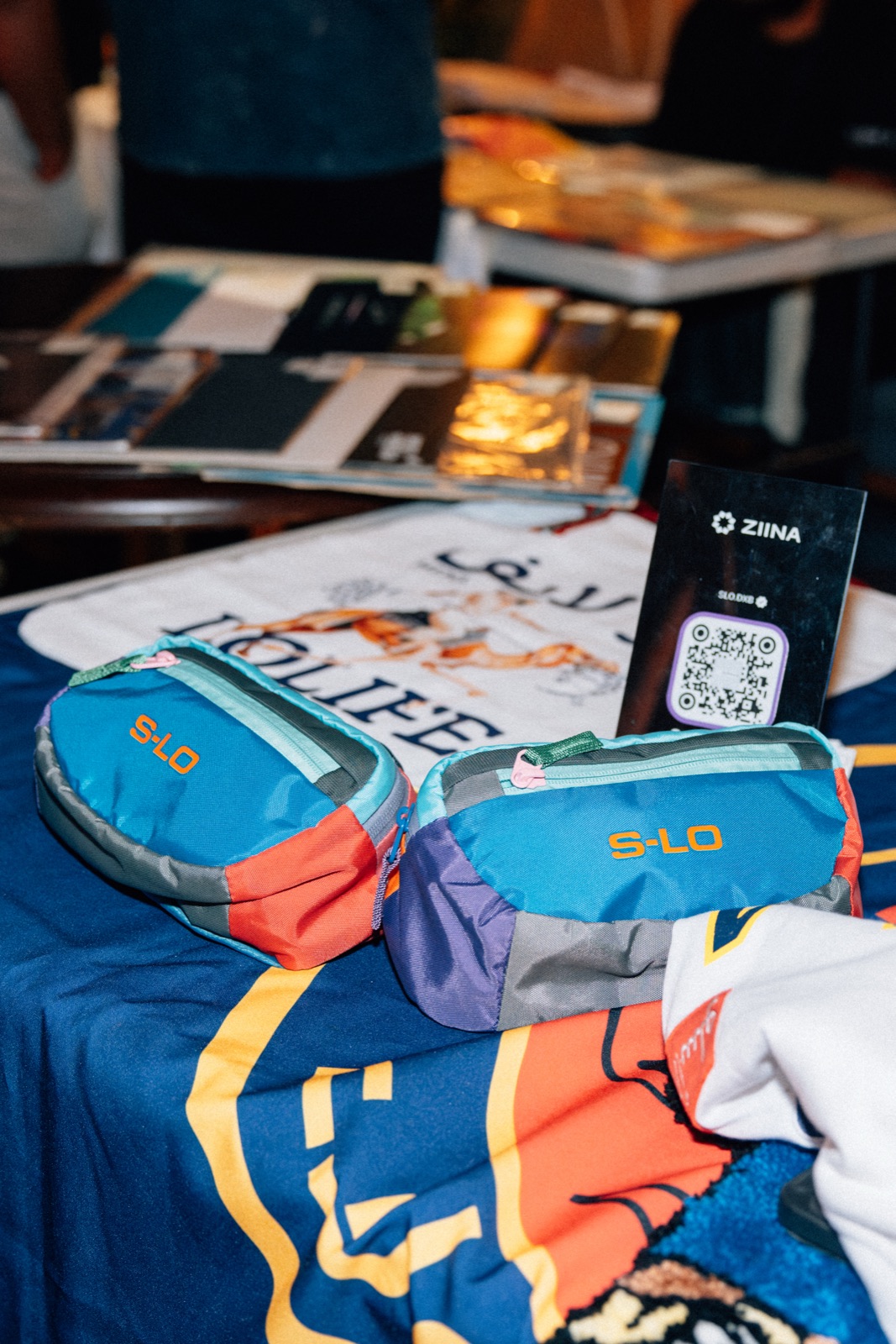 A stall table of printed bags and zines with a card reader.