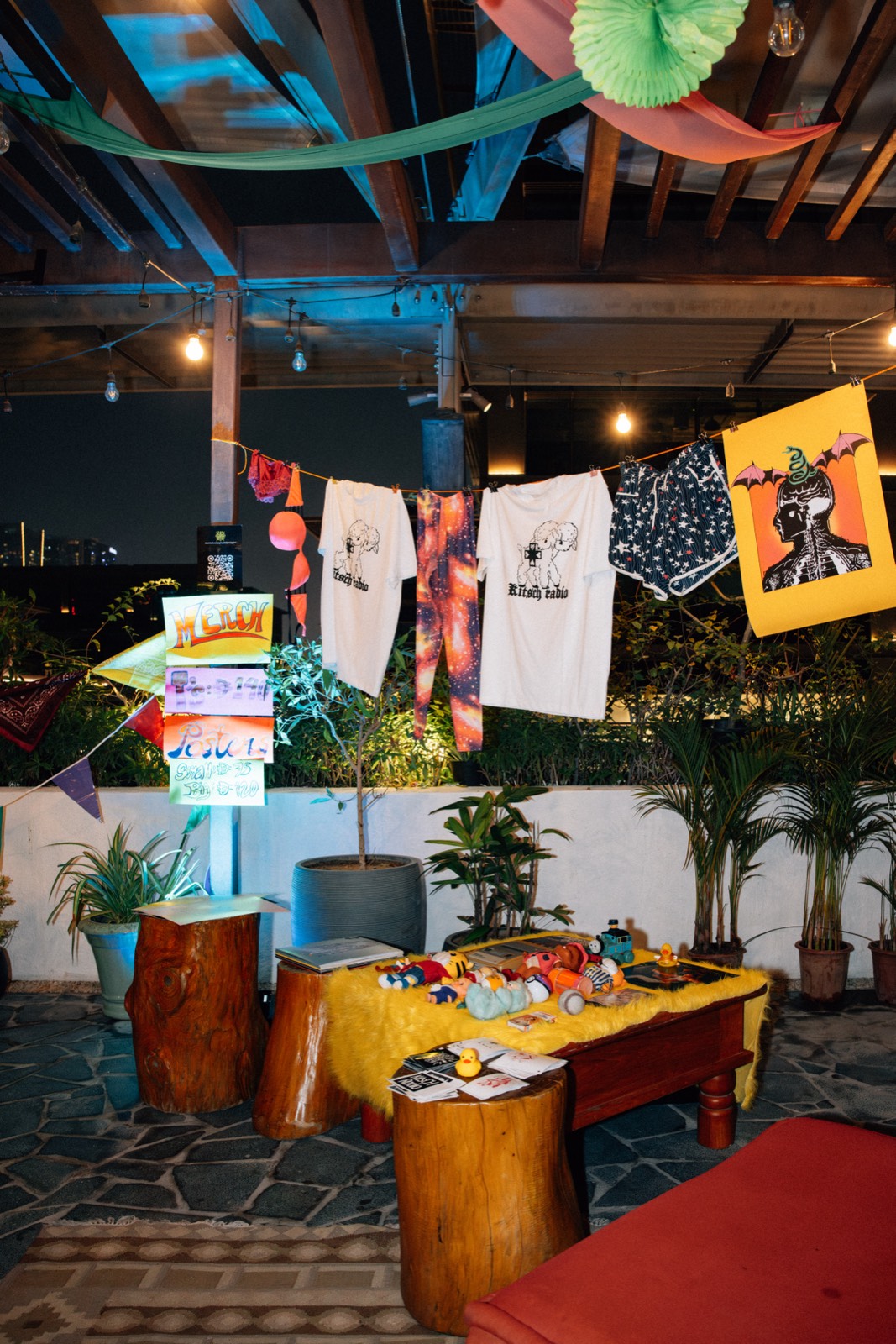 Printed T-shirts pegged on a line above a stall of prints and records.