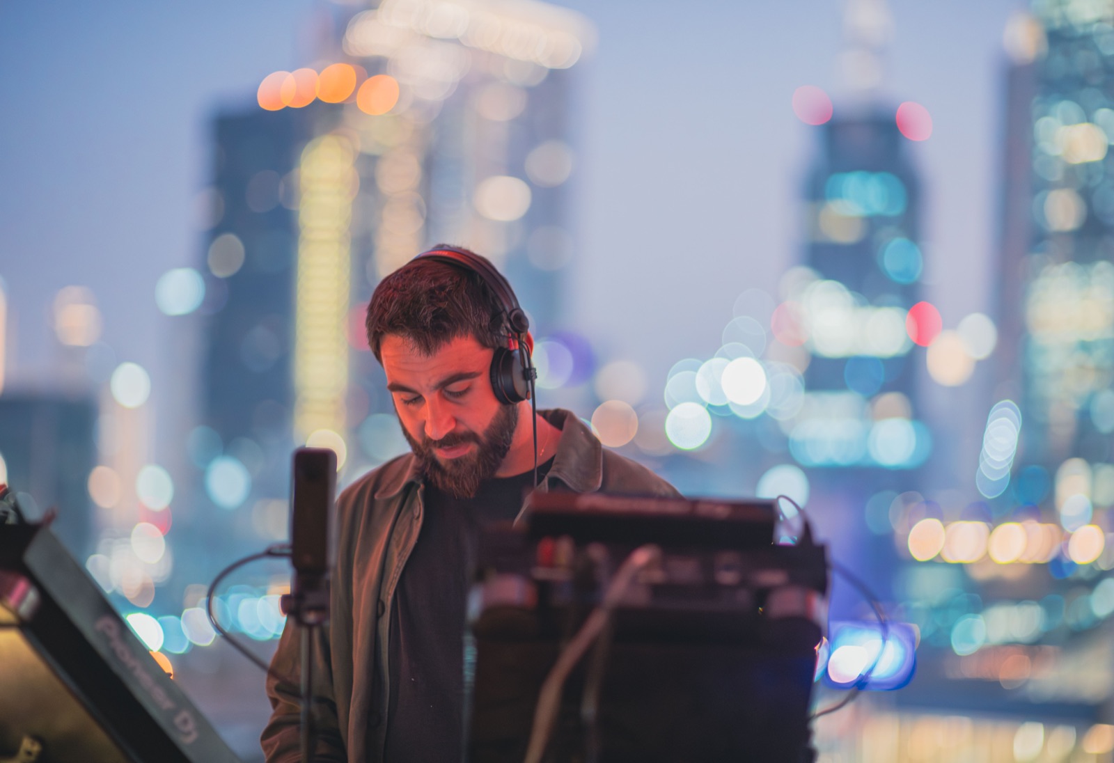 A DJ at the decks on the terrace, Dubai’s towers out of focus behind.