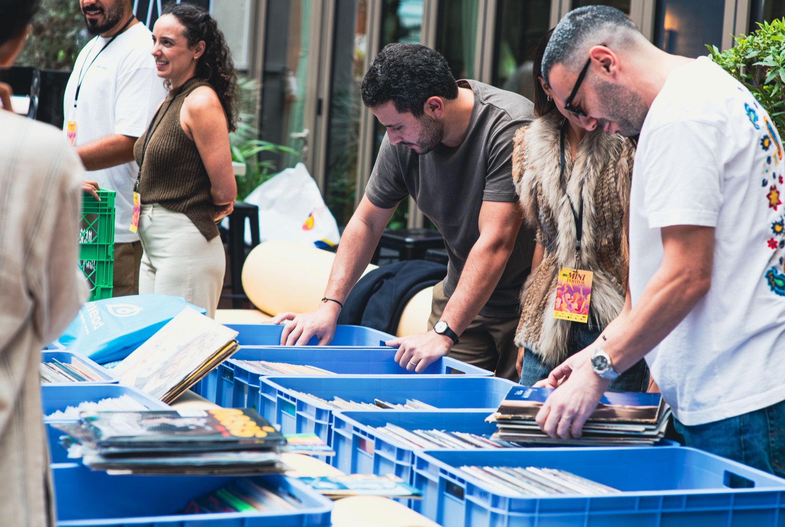 People flicking through blue crates of records at the fair.