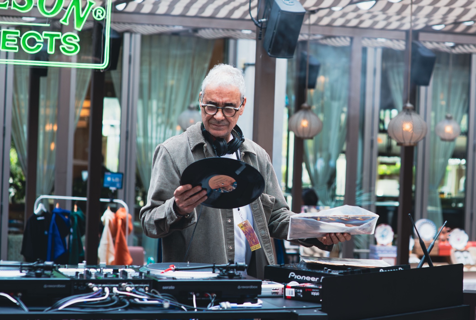 Someone holding a record up to the light beside the turntables.
