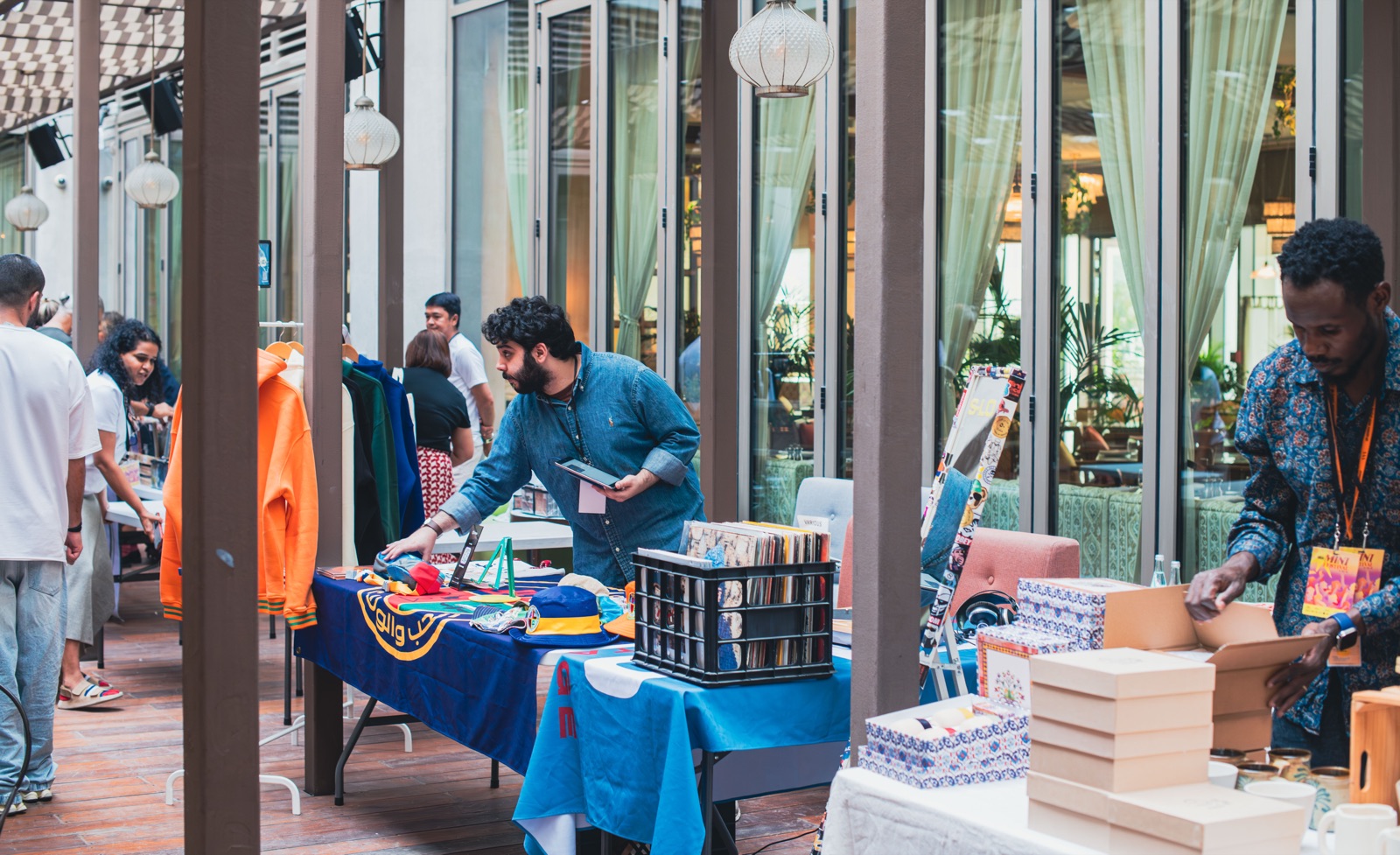 Stalls under the arcade: records, clothes and prints on blue-draped tables.