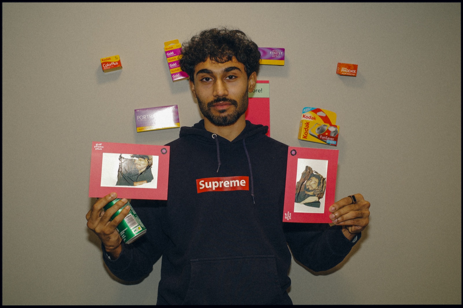 A man holding up two small framed photographs.