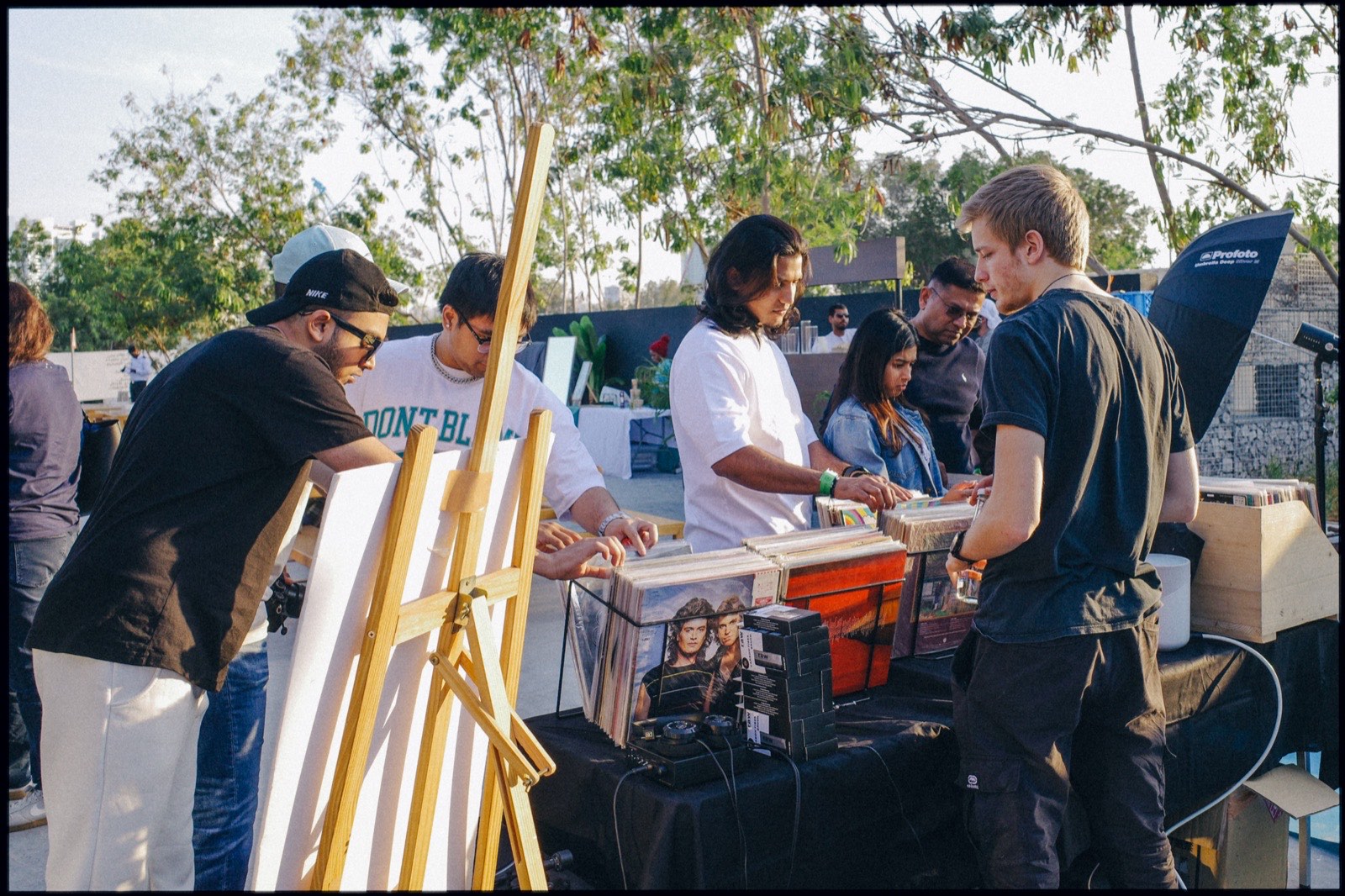 People browsing a stall beside an easel outdoors.