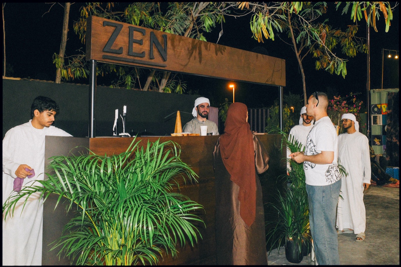 People at an outdoor bar lit by candles at night.