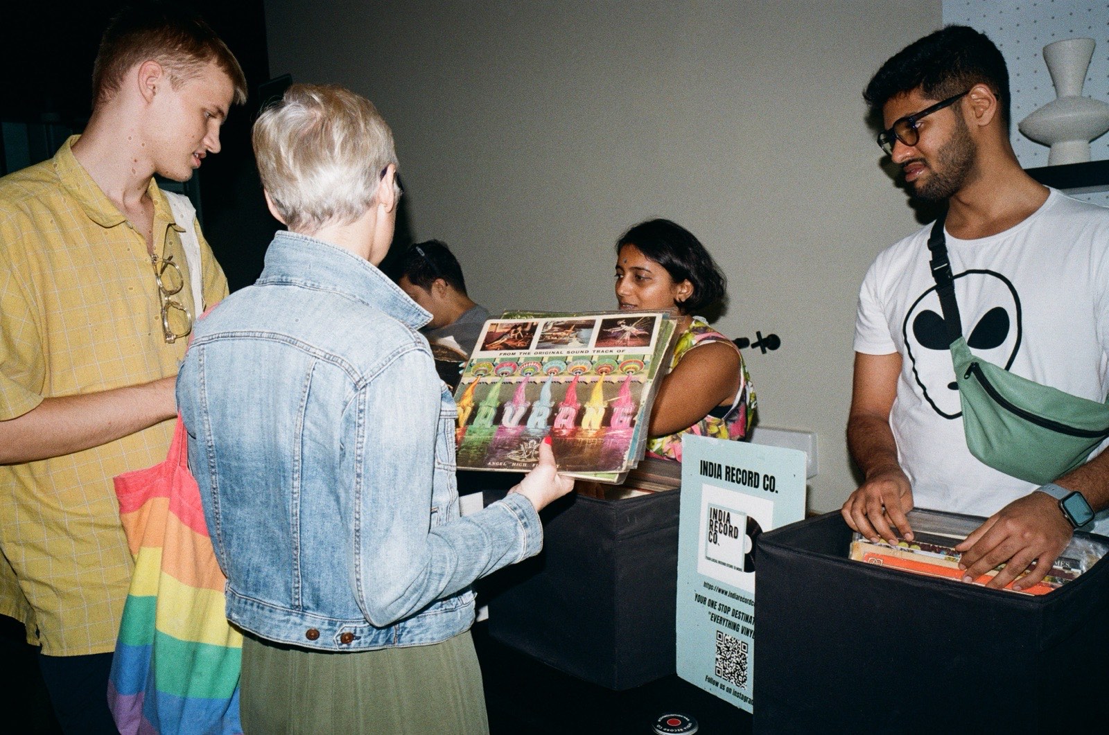 People browsing records at a stall, one holding a record up.