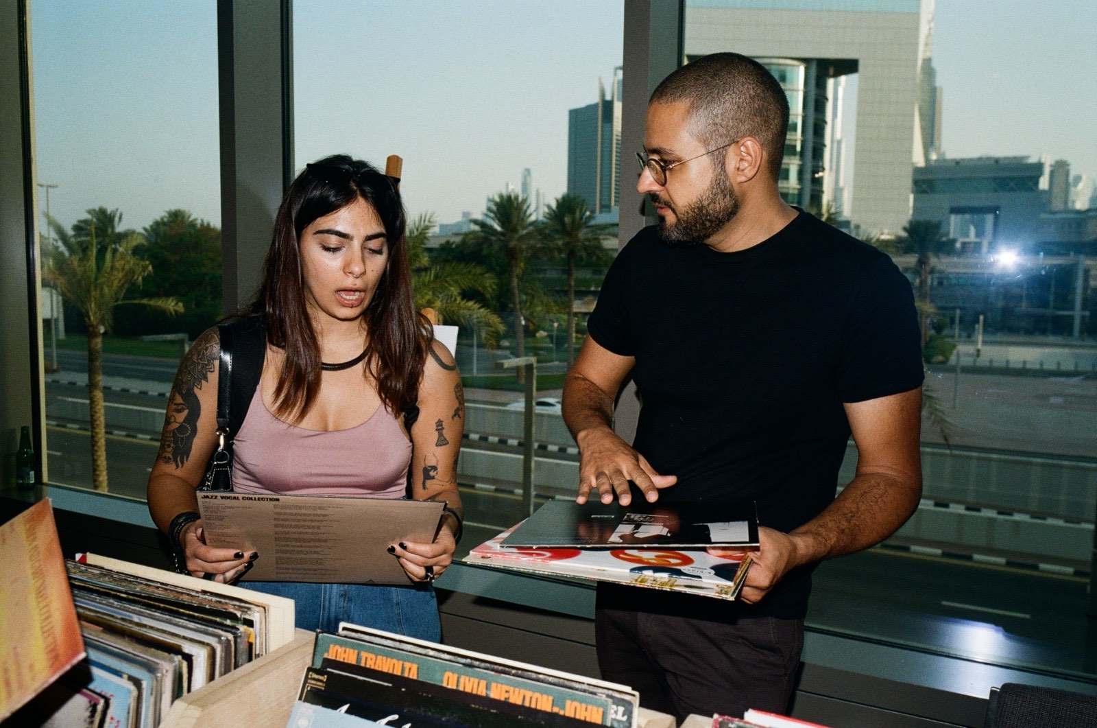 Two people browsing records by a window at sunset.
