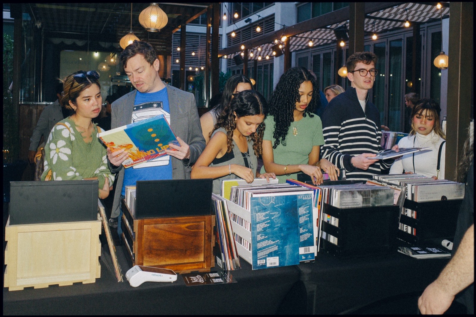 People browsing records and books at a row of stalls.