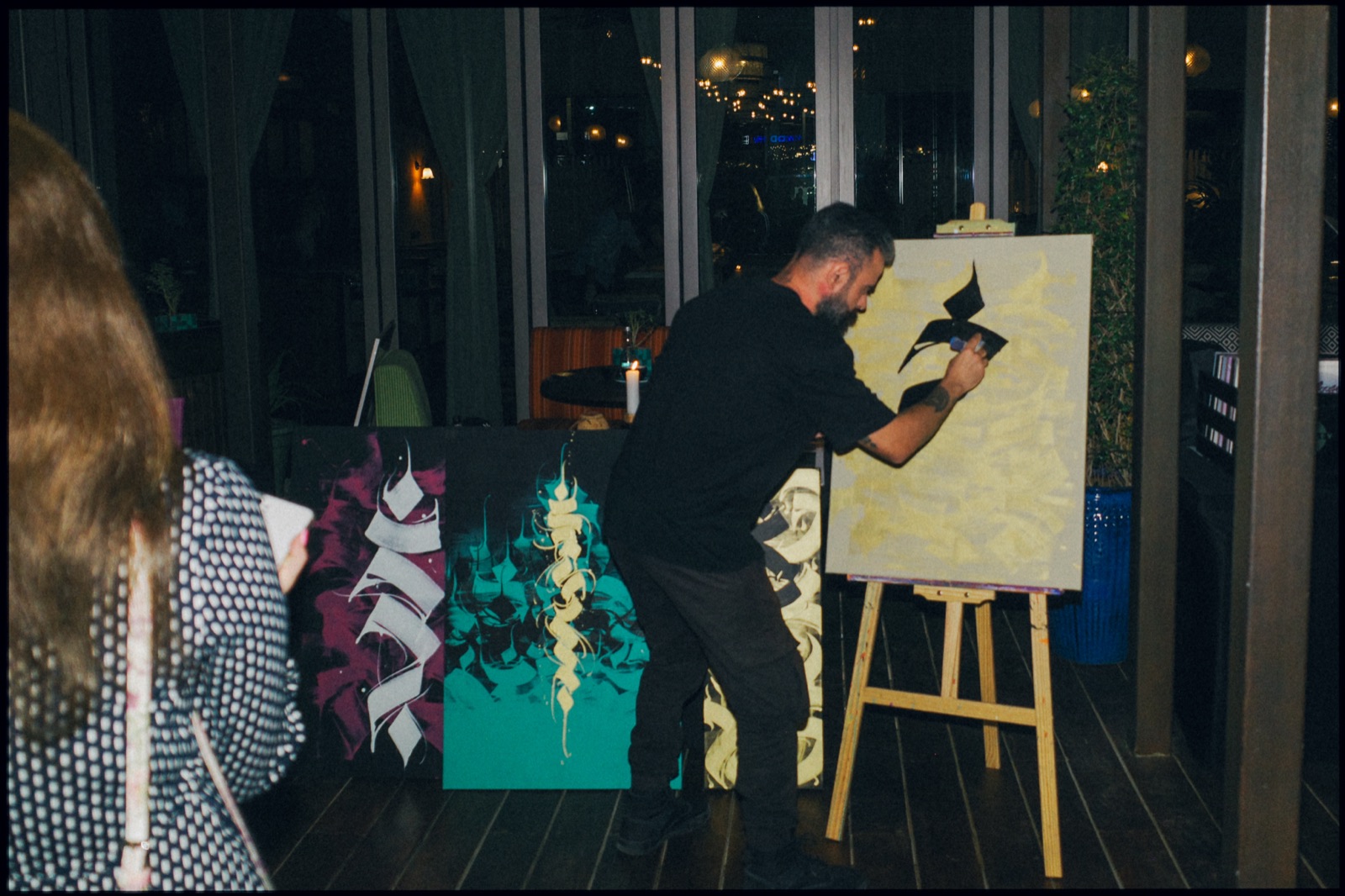 An artist painting on a canvas on an easel at night.