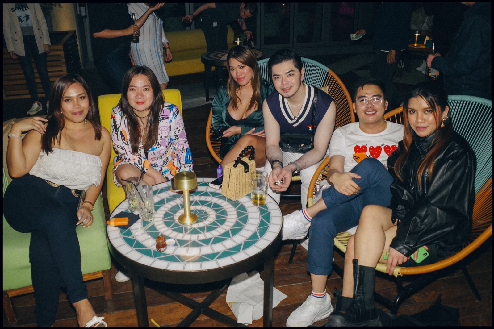 Friends sitting around a mosaic table at night.