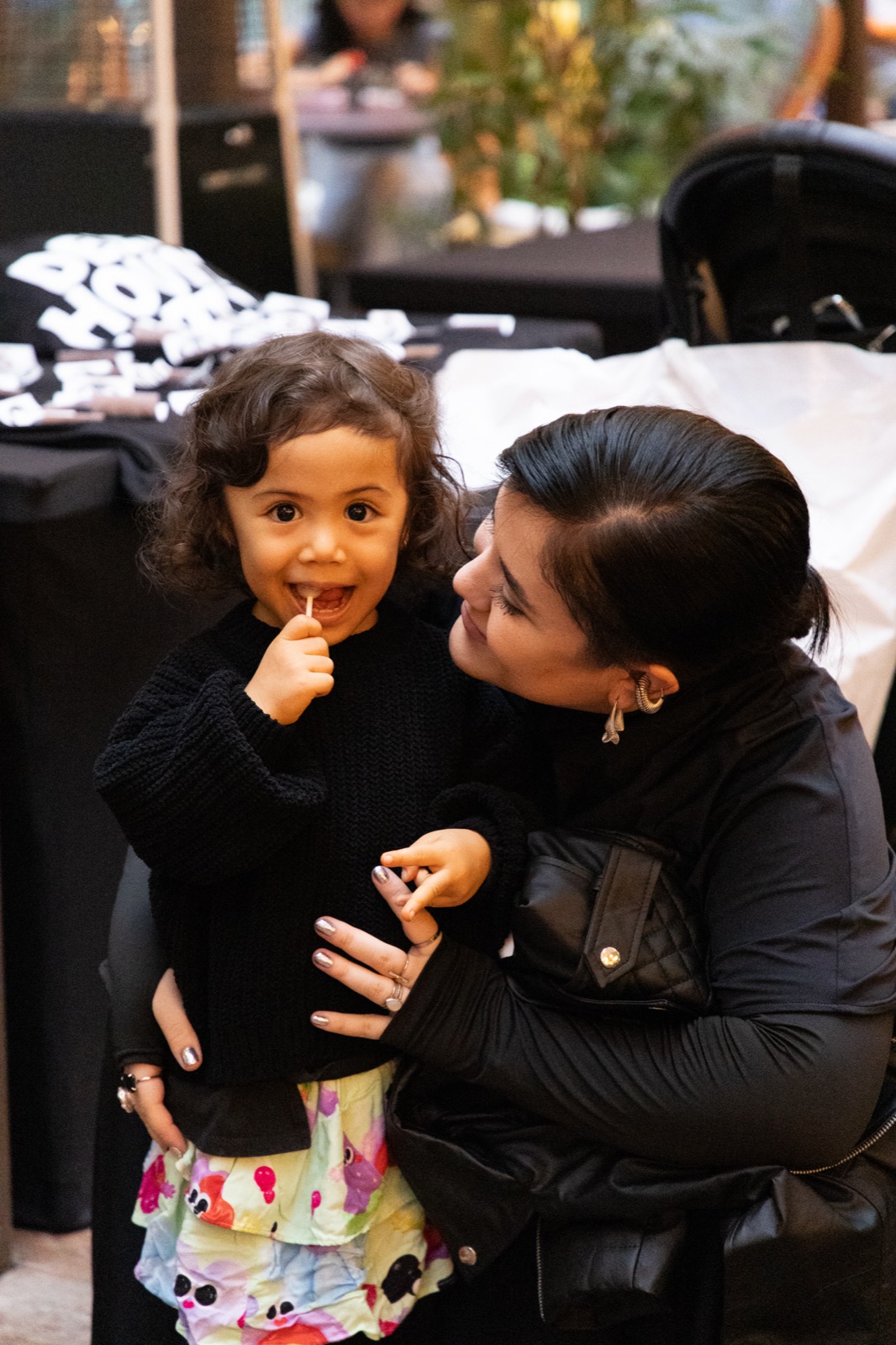 A child with a finger to their lips, held by a woman.