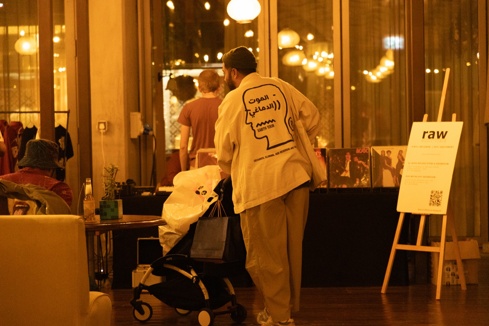 A person at a stall in a warmly lit room, beside a Raw sign.