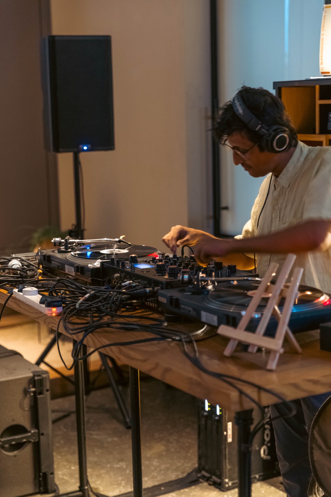 A DJ in headphones at a table of mixers and synthesisers.