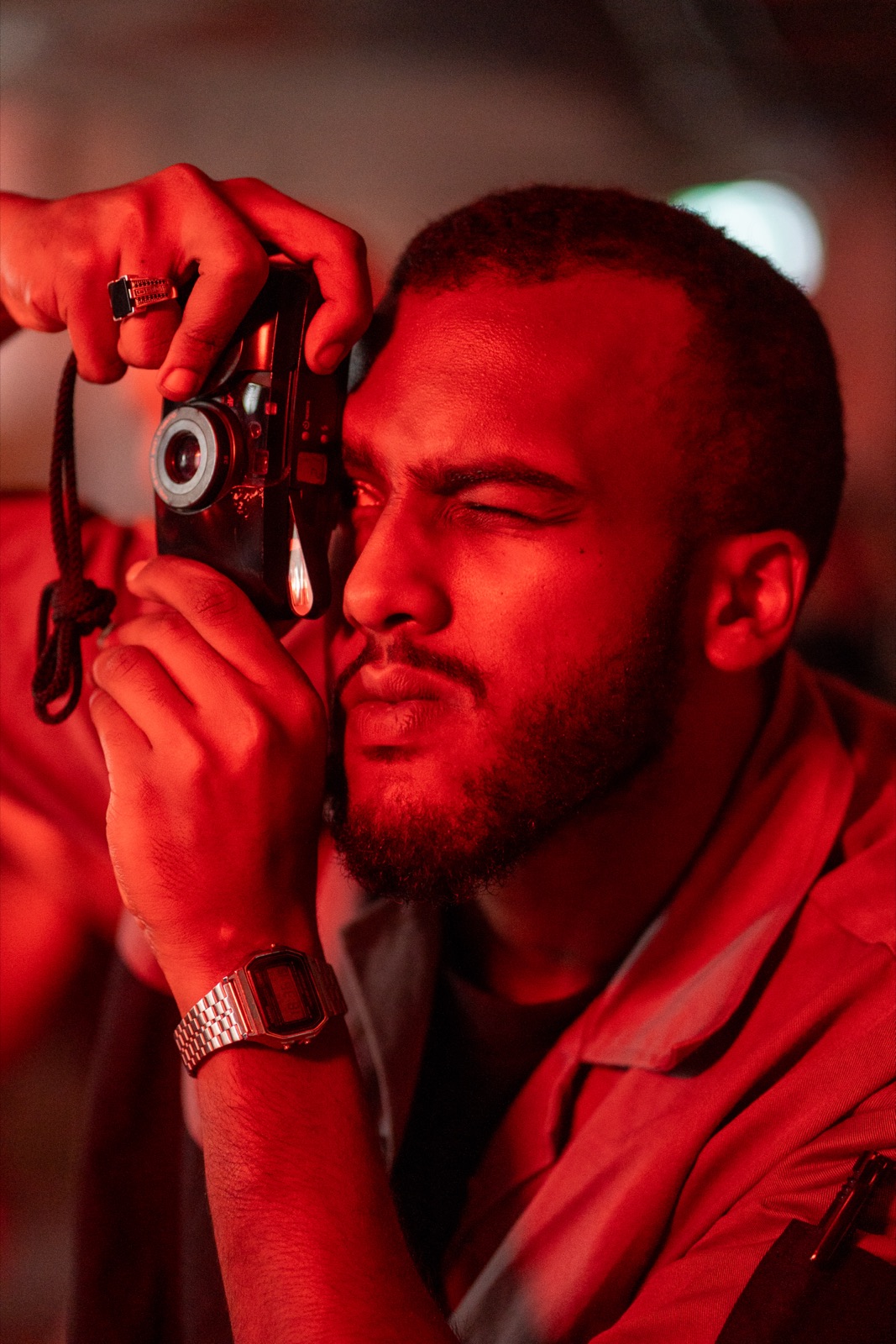 A man taking a photo with a film camera in red light.