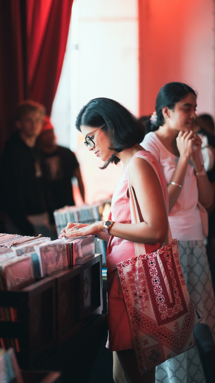 Two women browsing crates of records by a window.