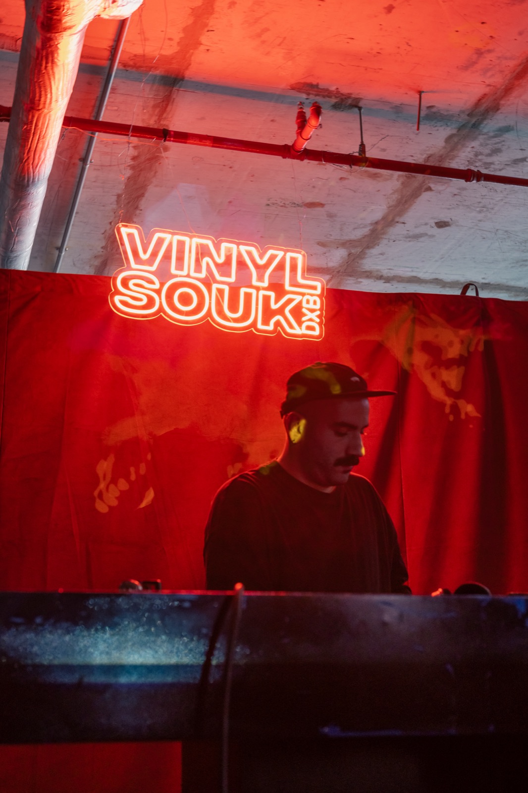 A DJ under a Vinyl Souk neon sign.