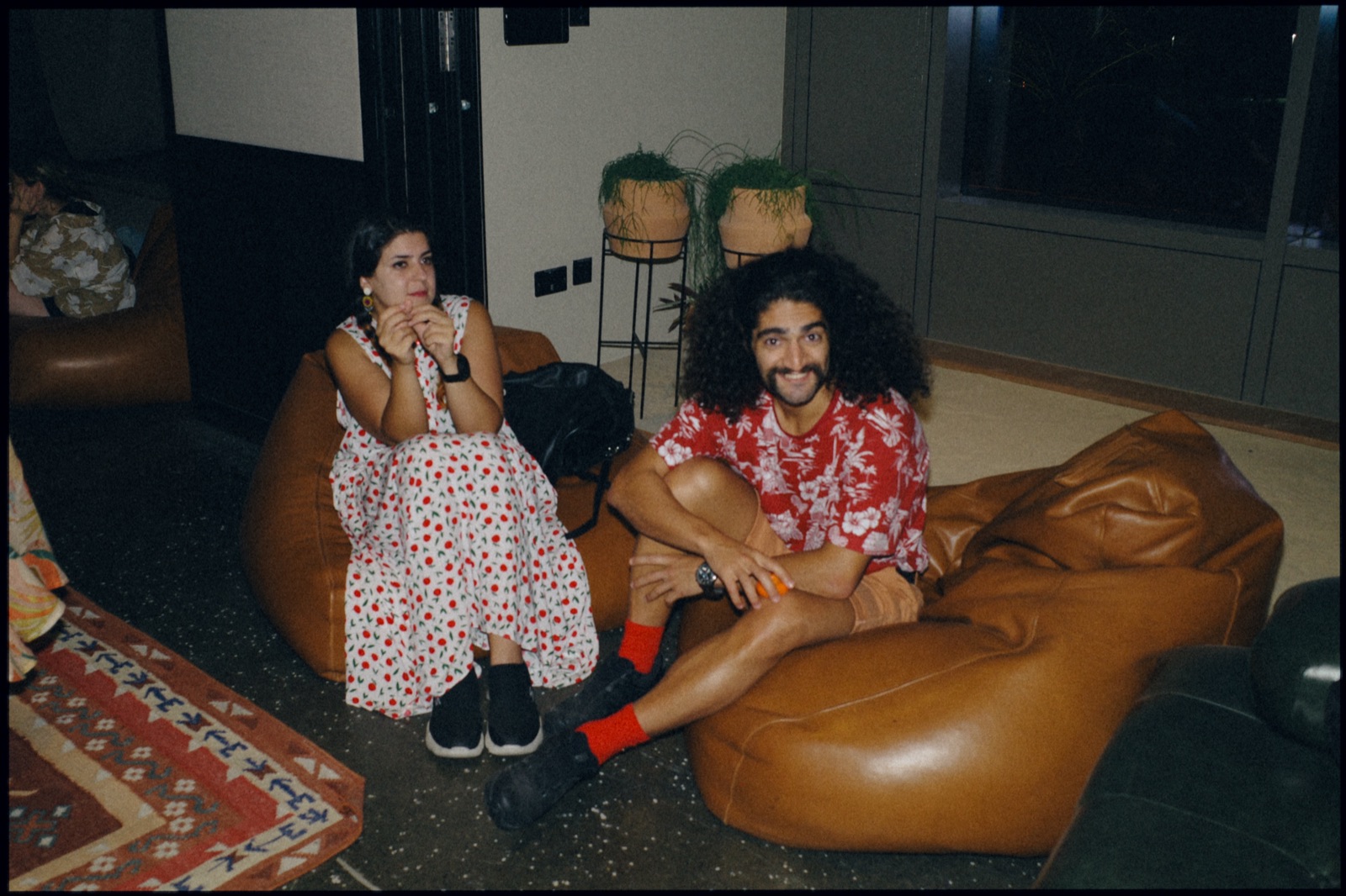 Two people laughing on leather bean bags.