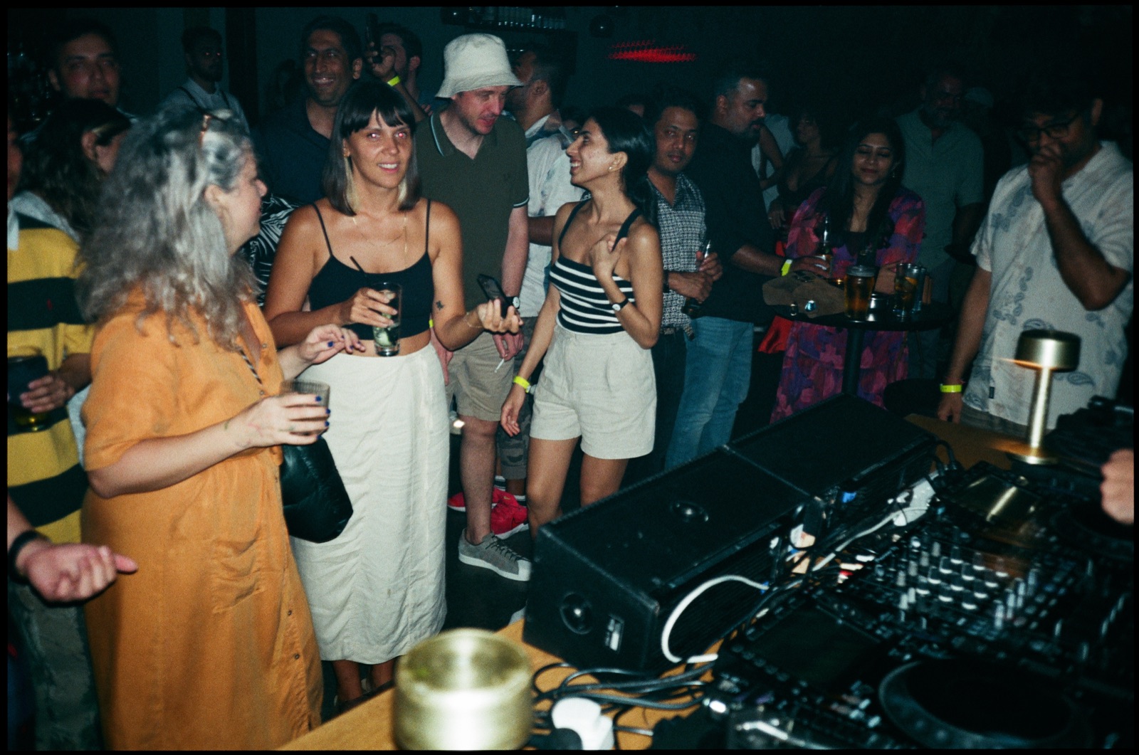 People dancing beside the DJ booth at night.