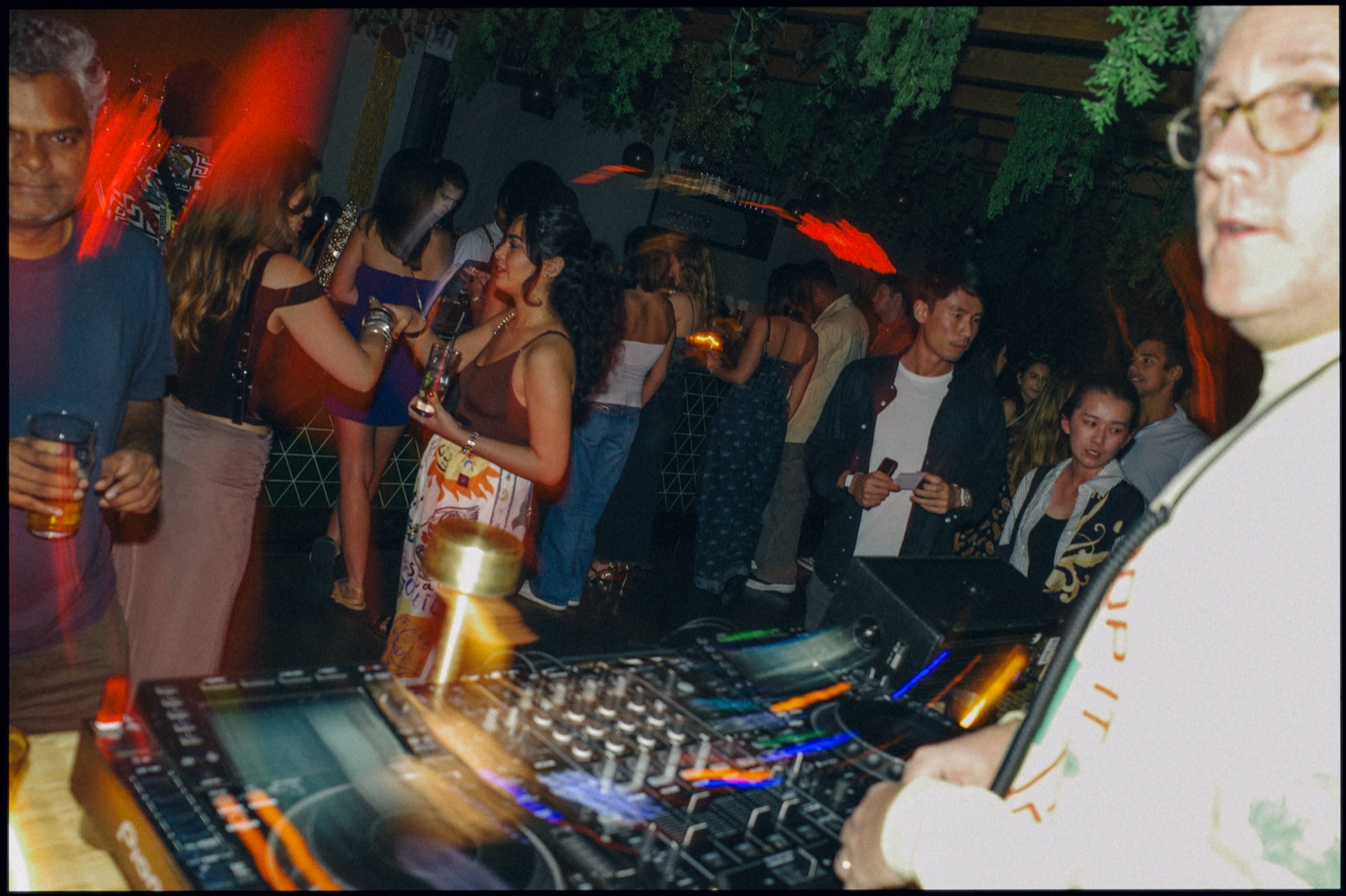 A crowd dancing at night, blurred with coloured light trails.