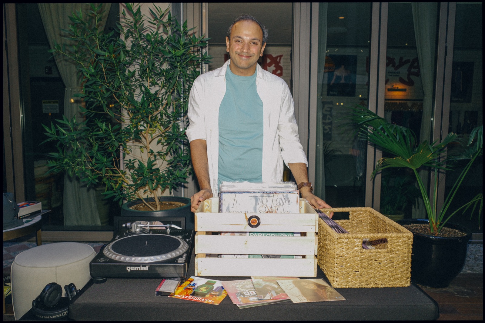 A man smiling behind a wooden crate of records on a stall.