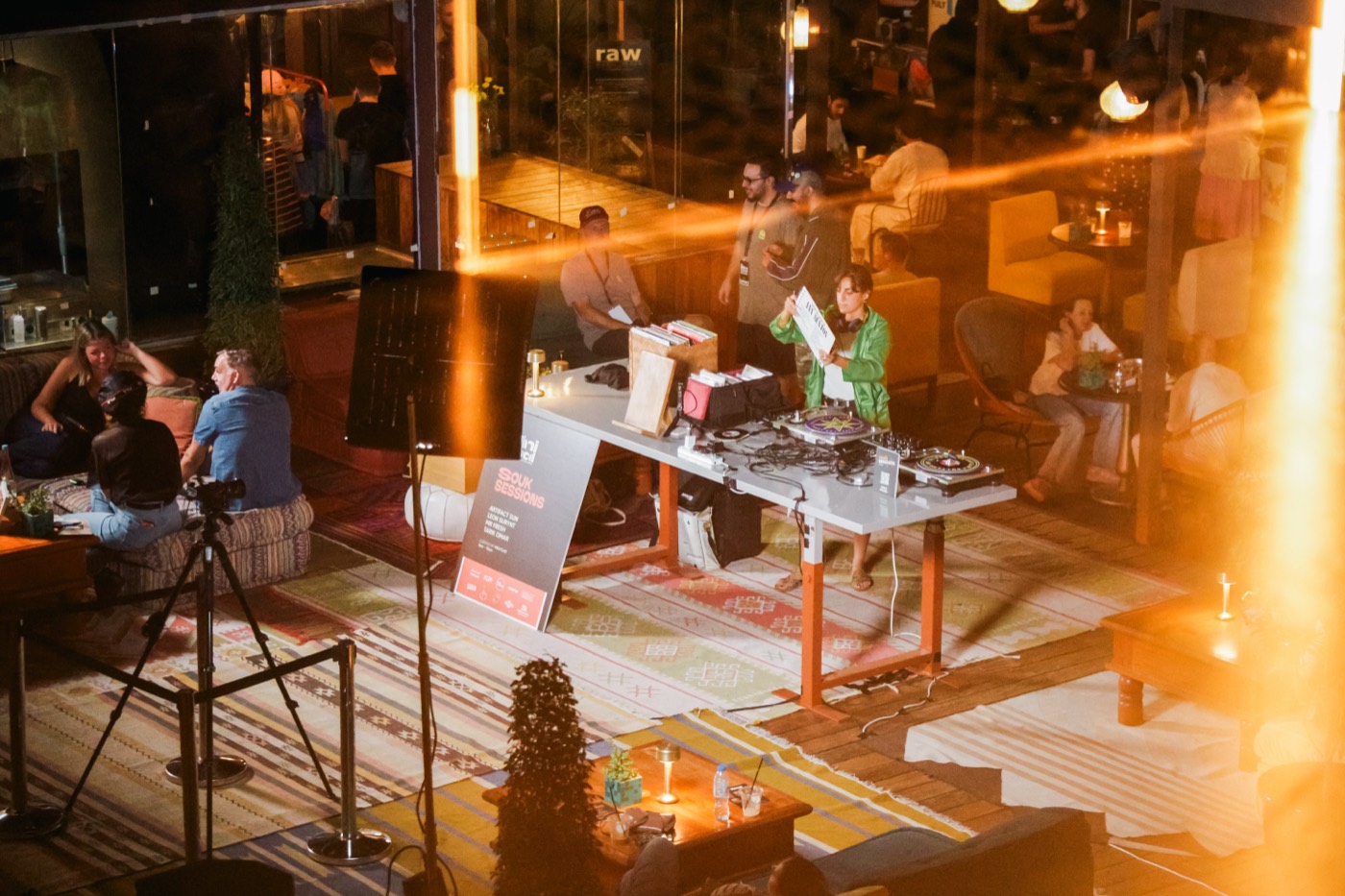 A DJ playing records on an evening terrace beside a Souk Sessions sign.